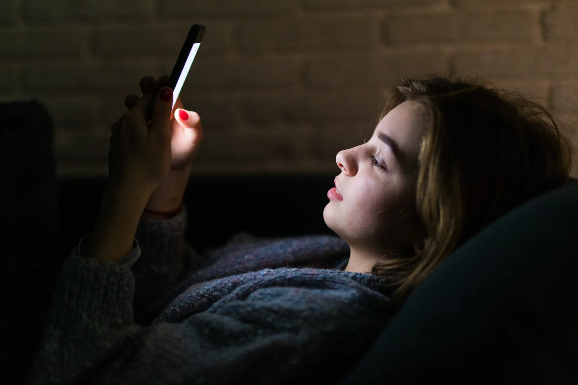 Woman using phone before bed, causing lifestyle disesase in a healthy body