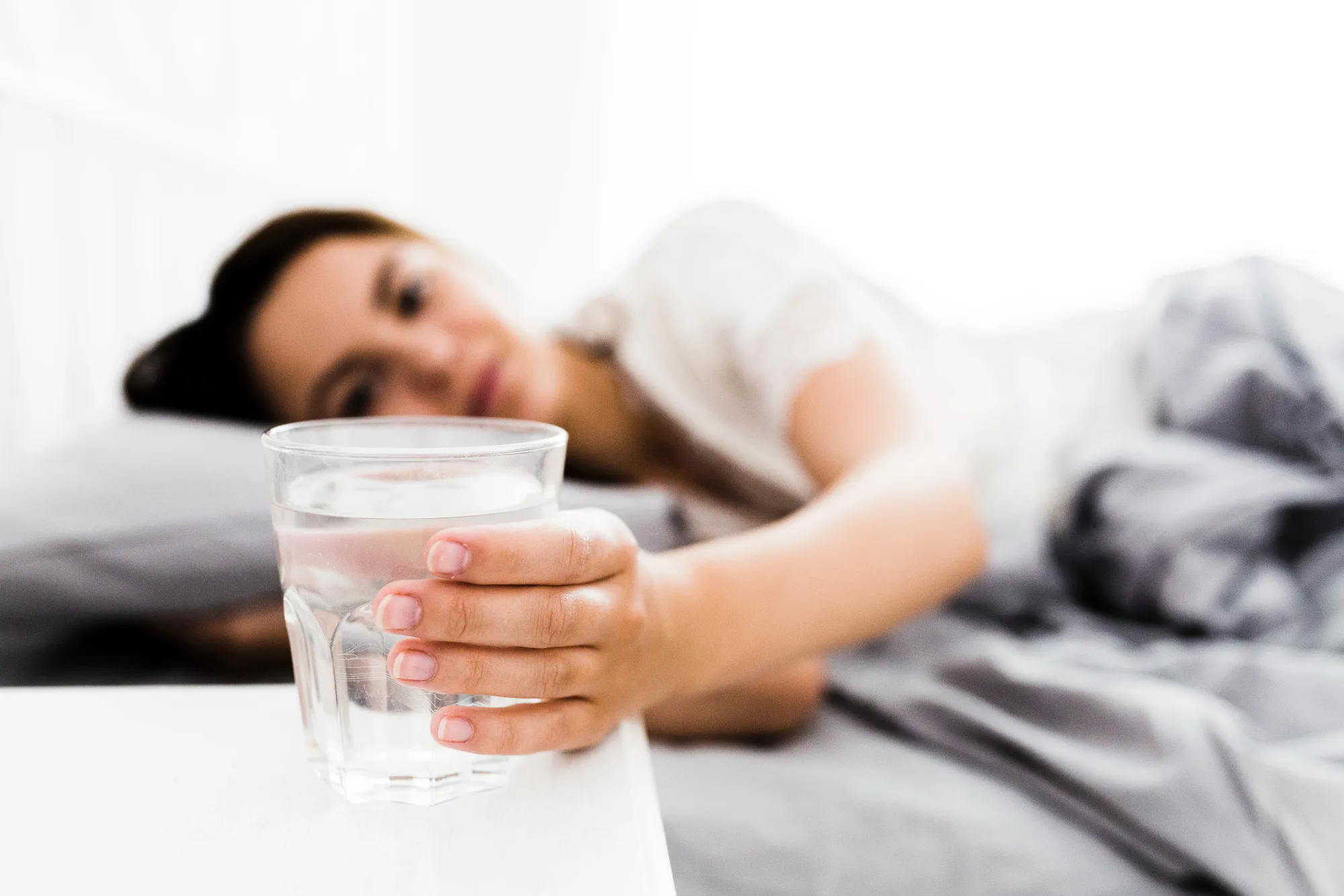 Woman with glass of water placed alongside for sound sleep