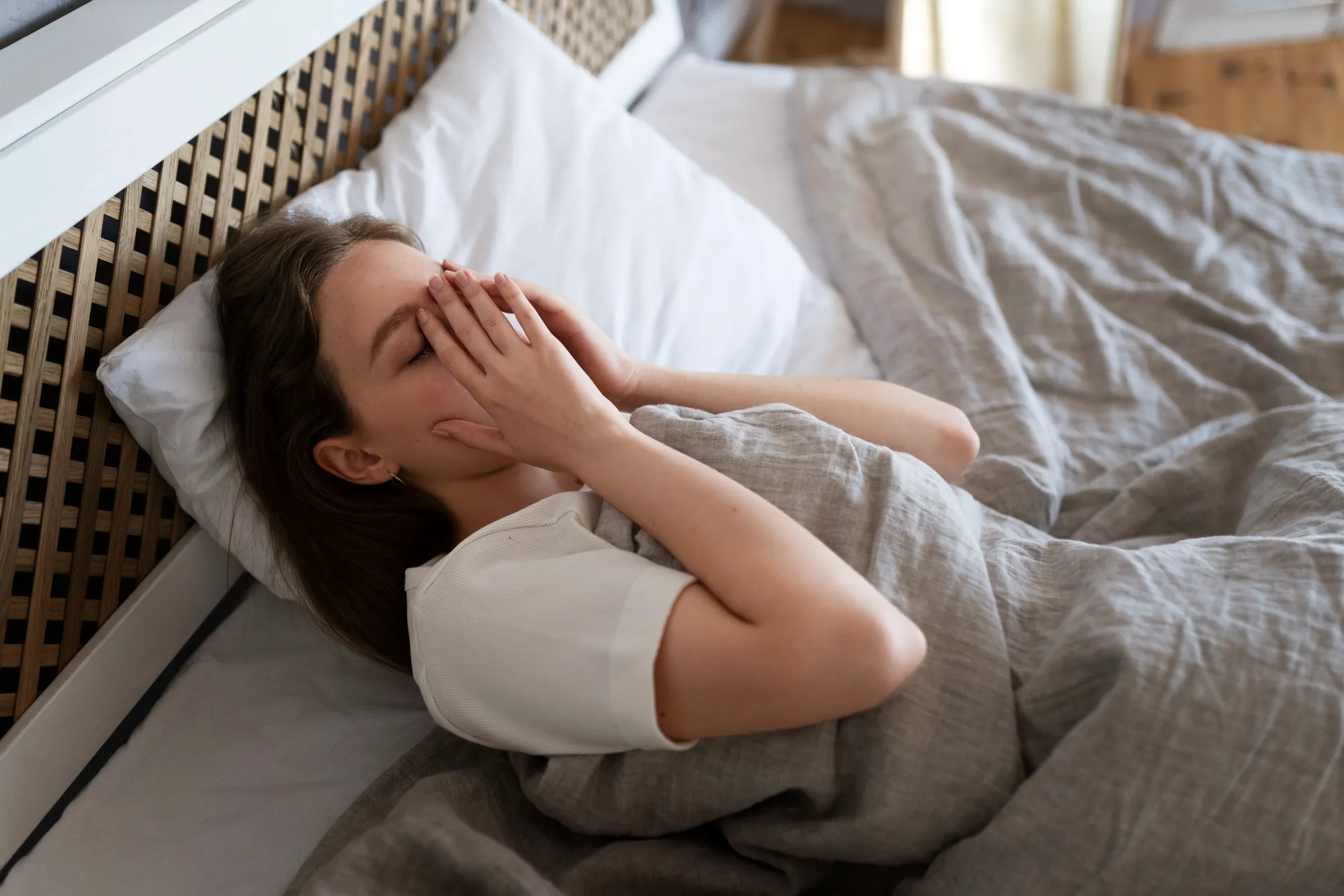 A woman trying to go sleep, having sleep anxiety symptoms like sweating and increased heartrate
