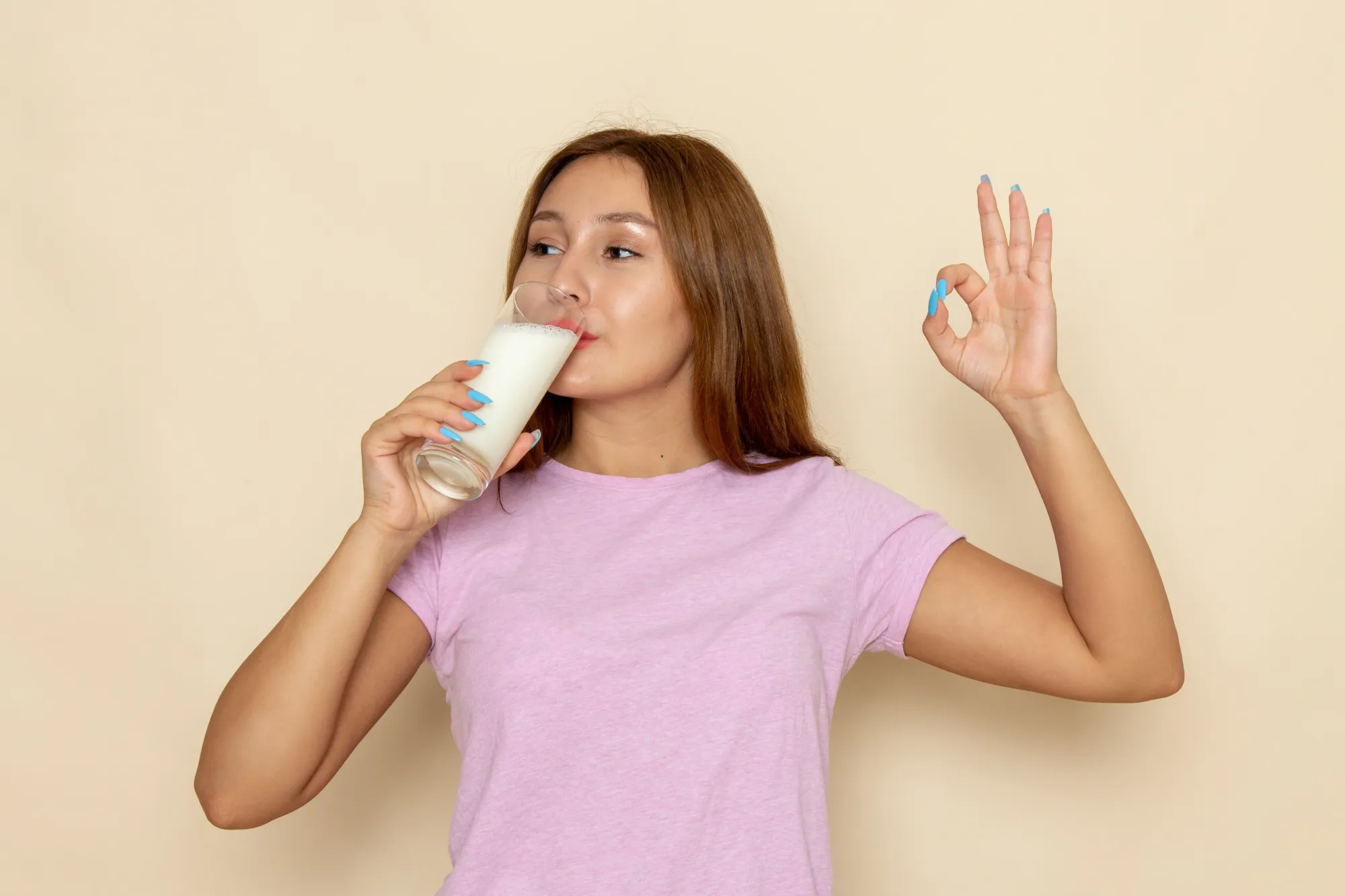 A woman drinking warm milk before bedtime as she's sleeping and she's hungry