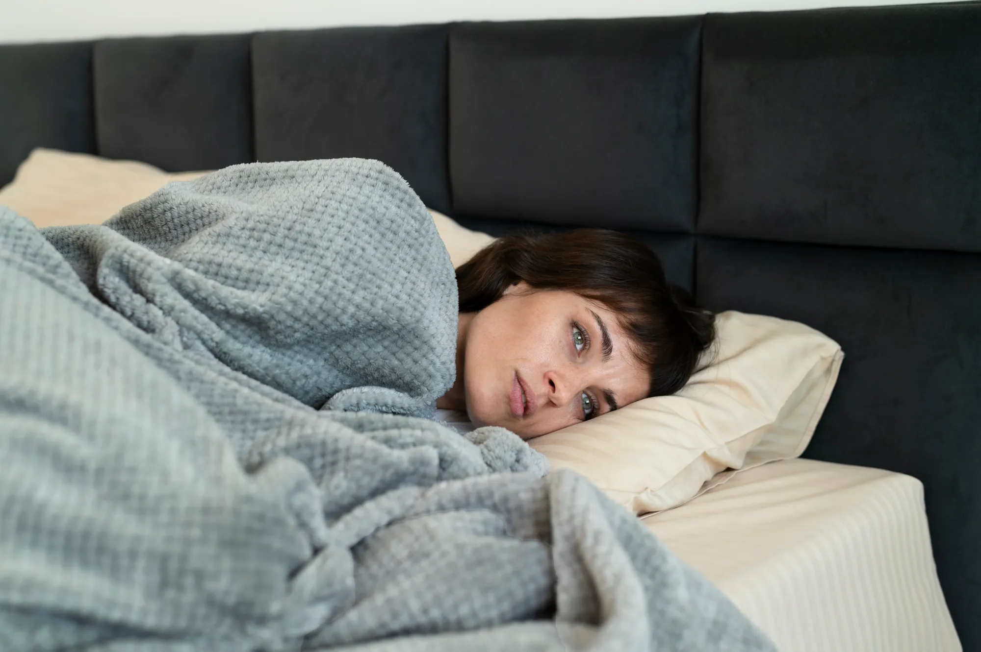 A woman with sleepy eyes finding it difficult to fall asleep faster at night