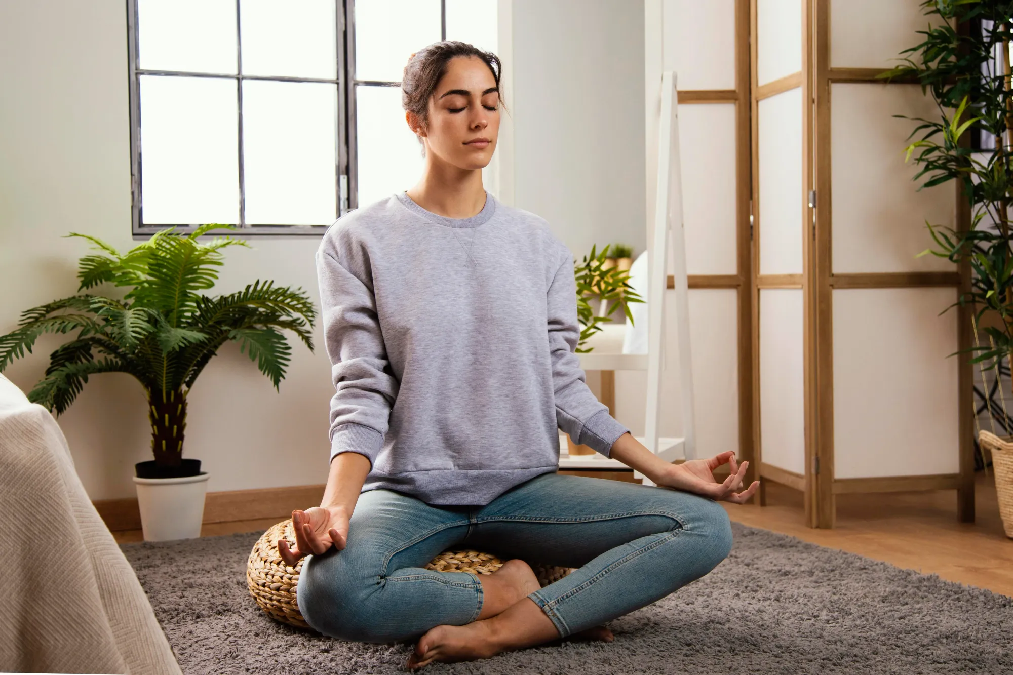 A woman sitting peacefully, doing meditation at home