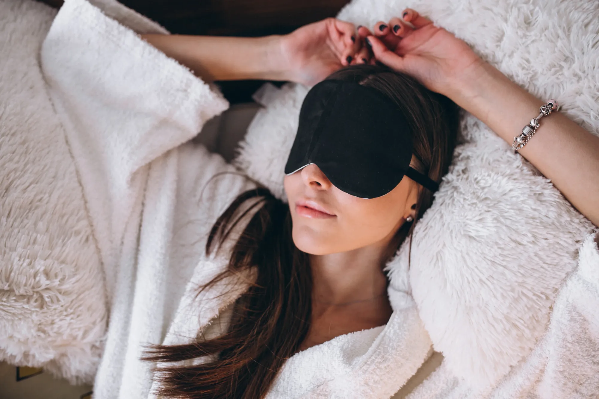 A woman wearing sleep mask while listening to relaxing sleep music