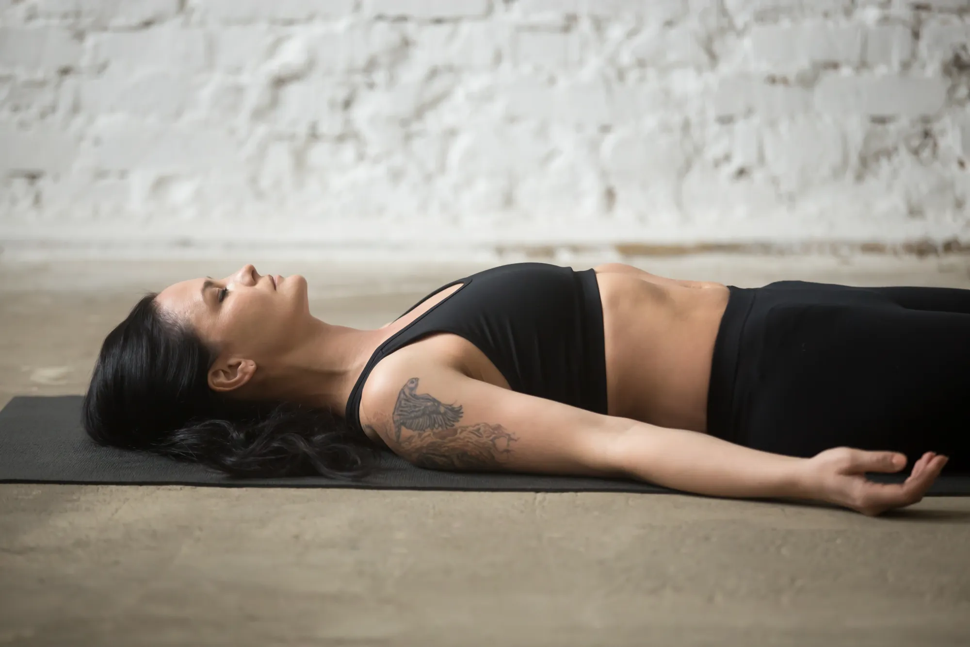 A woman lying in corpse pose doing yoga nidra to experience its benefits