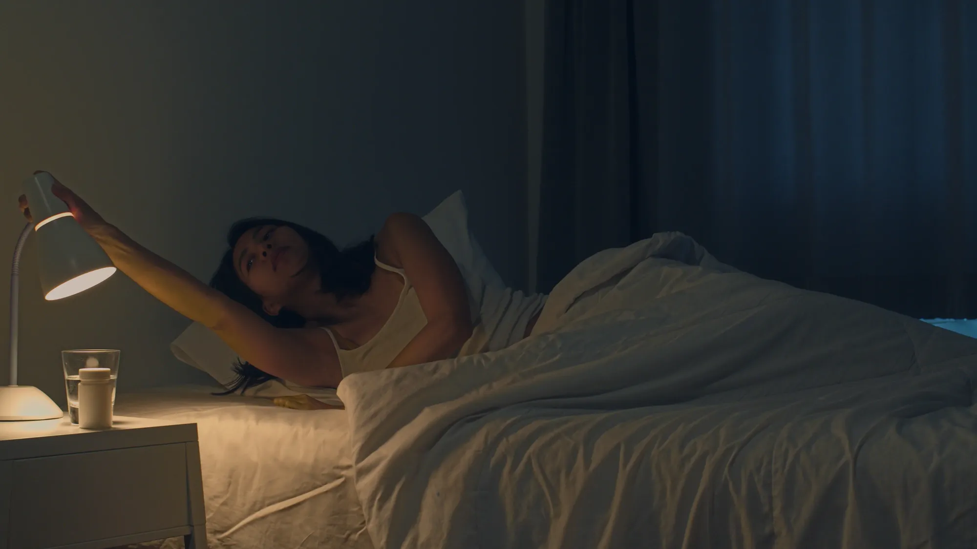 A woman switching off the light in a dark room listening to sleep songs to fall asleep