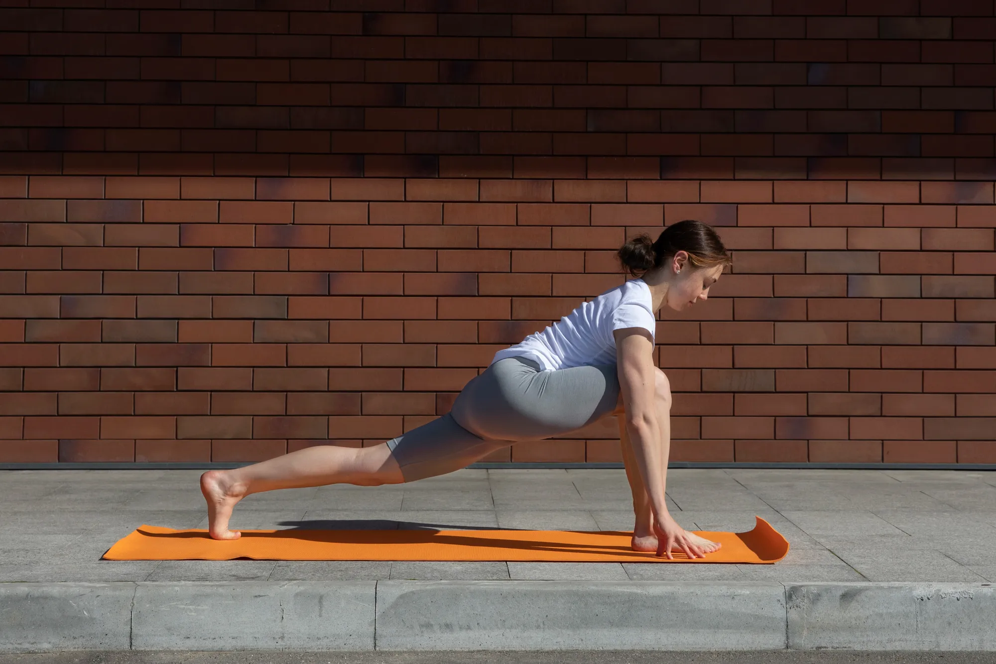 A woman practicing 12 poses of Surya Namaskar on a yoga mat