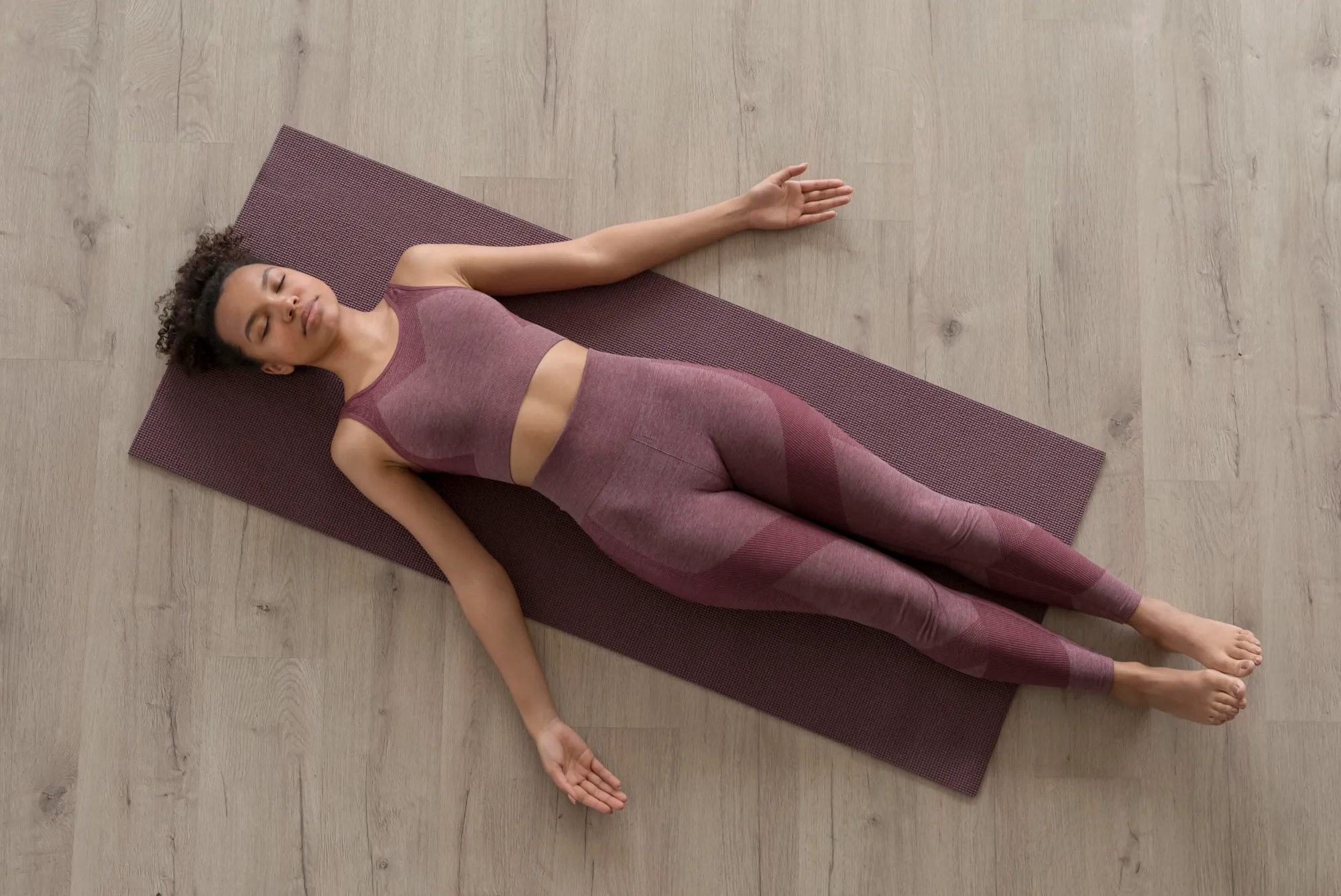 A woman lying in shavasana or corpse pose to do yoga nidra for anxiety