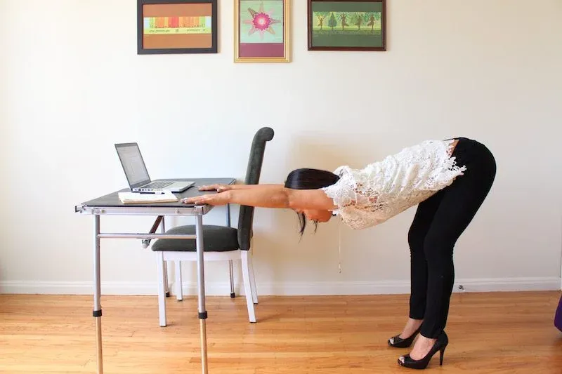 A woman doing Desk Downward Dog pose, a sitting yoga asana